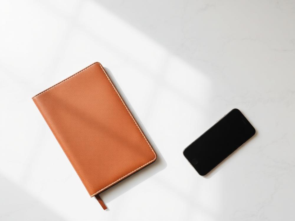 Notebook and phone on a marble desk in morning light